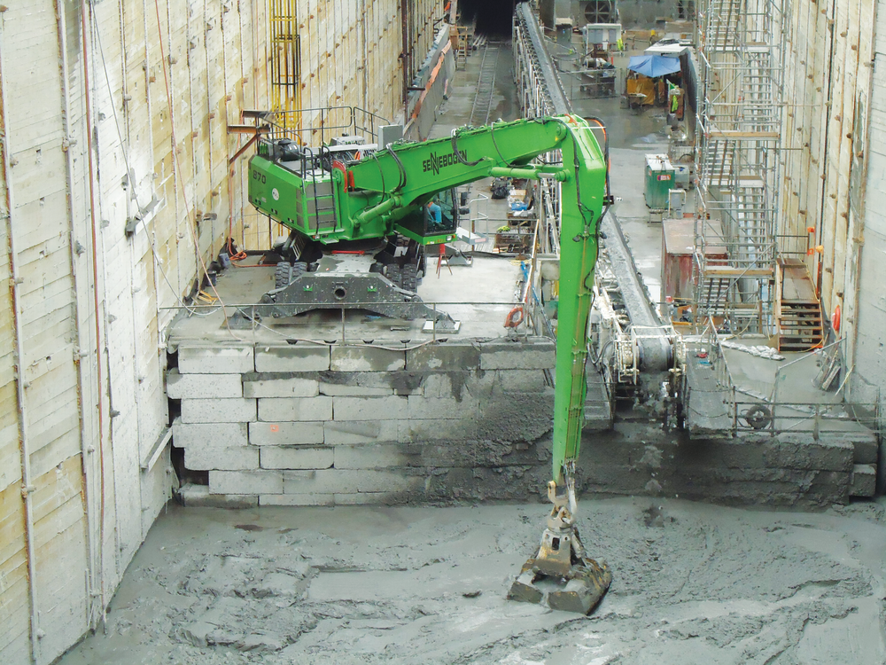 The operator of the SENNEBOGEN 870 M scoops up tailings with a custom clamshell bucket.