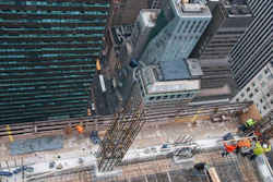 Looking down from above, workers use the top floor of the five story DOKA self-climbing deck system to erect column reinforcement.