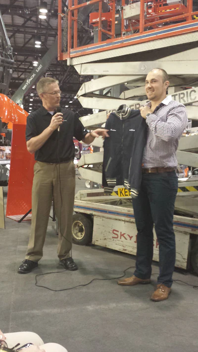 Matthew Kraner, co-owner of Kraner Electric Ltd. in Guelph, Ontario, Canada, is shown accepting a vintage jacket that commemorates the honor of owning the oldest working Skyjack scissor lift.