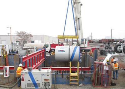 Ground level view of the excavation, showing proximity to an active rail yard, as Microtunnel machine is lowered into the shored excavation.