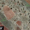 Figure 1: Reflected light photomicrograph of polished surface showing dark, low w/cm mortars (green bars) coating aggregate particles. These are typical indicators of retempering.
