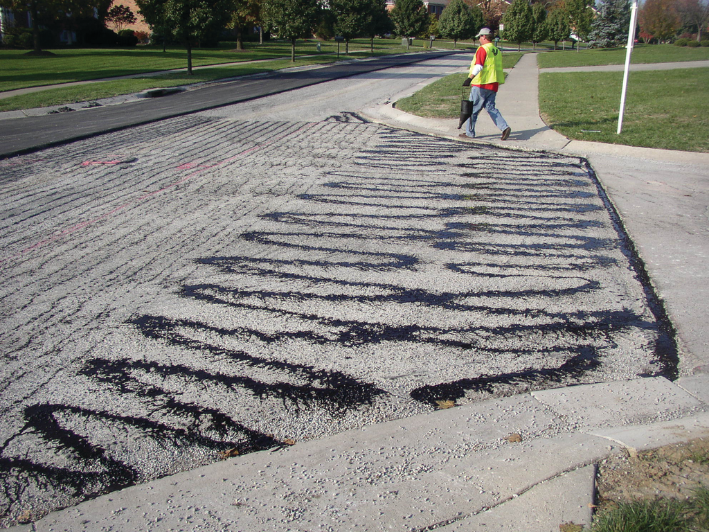 Improper application of tack coats, like this tack that was applied by hand using a pour bucket, eliminates any benefits that can result from using tack coats to improve paving.