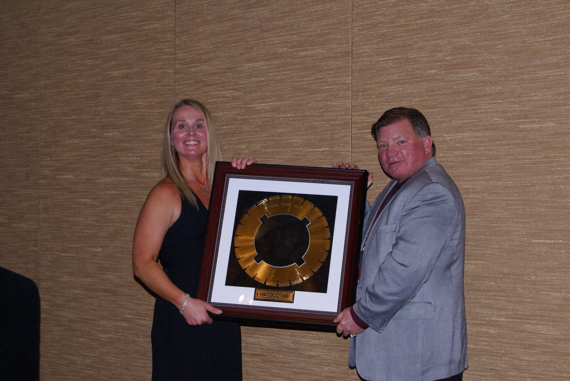 Mitzi McIntyre, Executive Director of the Utah Chapter of the American Concrete Pavement Association (ACPA), receives the 2014 Concrete Pavement Restoration (CPR) Promoter of the Year Award from John Roberts, Executive Director of the IGGA.