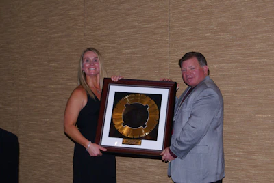 Mitzi McIntyre, Executive Director of the Utah Chapter of the American Concrete Pavement Association (ACPA), receives the 2014 Concrete Pavement Restoration (CPR) Promoter of the Year Award from John Roberts, Executive Director of the IGGA.