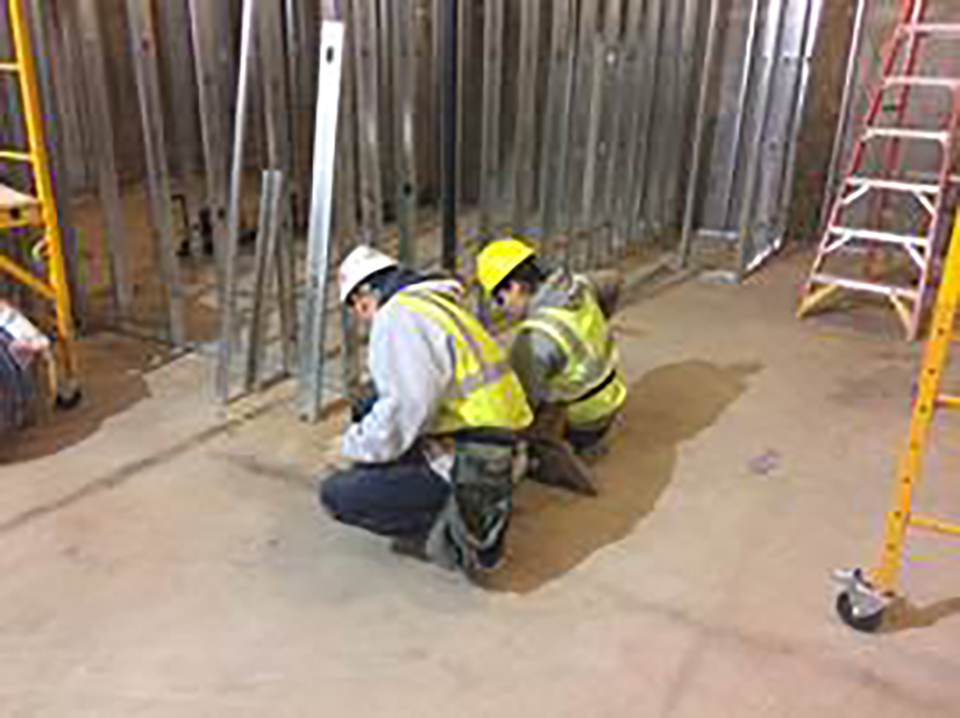 YouthBuild Boston student working with Century Dry Wall foreman laying out bottom track of wall framing for Suffolk Construction’s management offices in the Millennium Tower.
