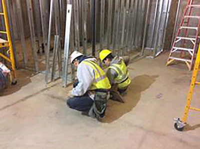 YouthBuild Boston student working with Century Dry Wall foreman laying out bottom track of wall framing for Suffolk Construction’s management offices in the Millennium Tower.