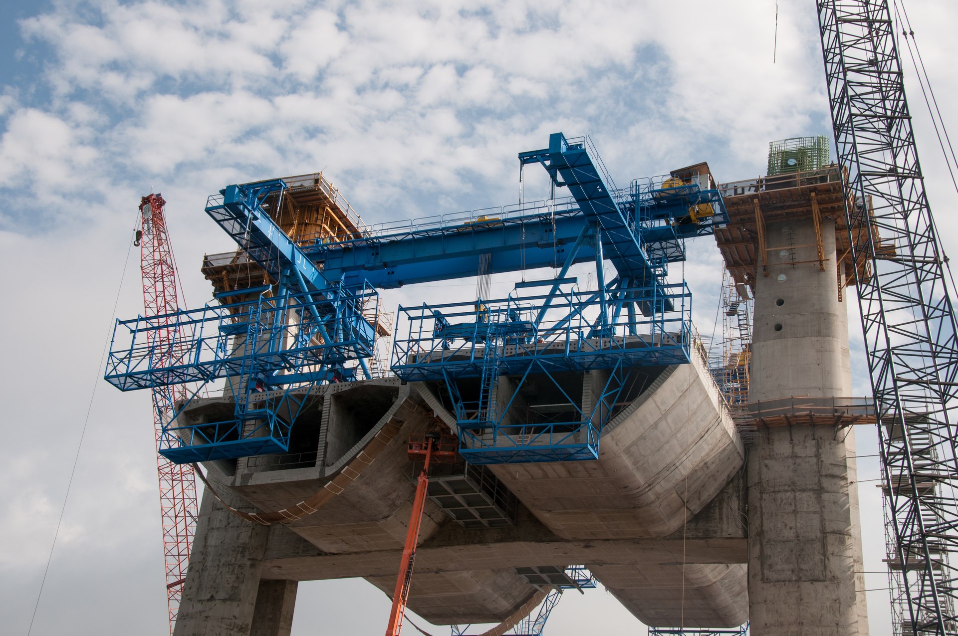 The new St. Croix River crossing between Minnesota and Wisconsin near Stillwater is an “extra-dosed precast segmental” structural concrete bridge. Shown here are the first three 180 ton segments on either side of the pier, held in place by post-tensioned tendons. The blue device is called a “segment lifter” and it also supports a working platform on the edge of the segment that iron-workers use to do the cable tensioning.