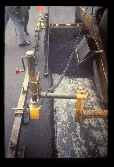 This is the proper amount of mix overlap from lane 2 to lane 1. In this case, the amount of overlap is in the range of 1 to 1-1/2 inches. Given this amount of overlap, no mix has to be moved off of the top of lane 1. No raking of the mix at the longitudinal joint is needed.