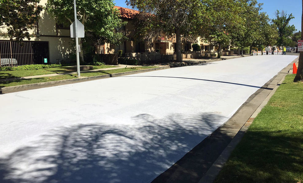 Workers apply a cool pavement coating to a street Saturday May 20, 2017 in Canoga Park. The coating is designed to reduce temperatures on the the surface of streets during Southern California heat waves.