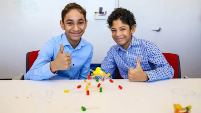 Two students from DREAM show off the tower they built using gummy bears and toothpicks.