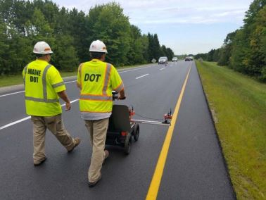 Operators scan a pavement section. Readings are processed as a line chart.