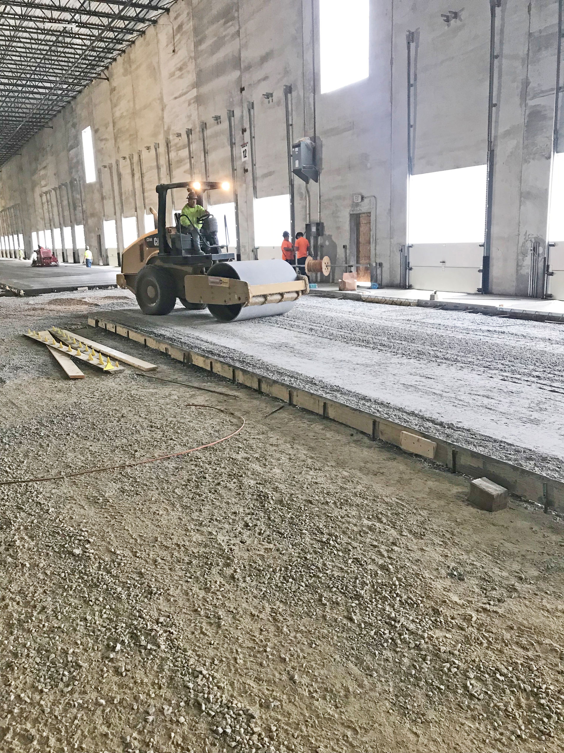 Base course being compacted with vibratory roller.