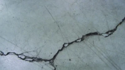 Unrestricted crack width growth leads to spalled edges along out-of-joint cracks when exposed to wheeled traffic.