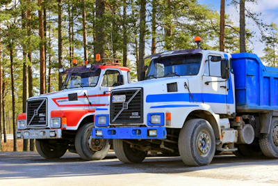 Heavy-duty trucks on asphalt yard.