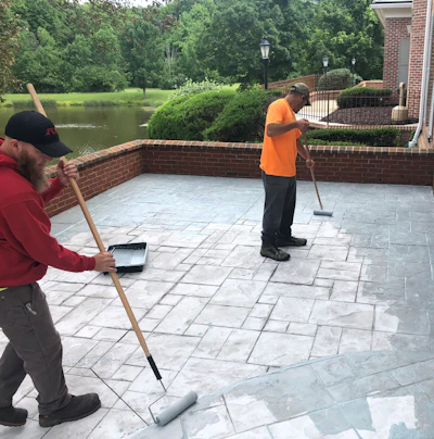A spray-applied topping resurfacer can rejuvenate worn stamped concrete by filling imperfections, restoring color, and providing a durable, fresh finish that enhances the original design.