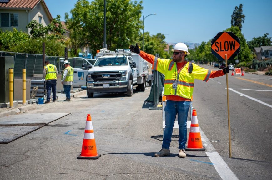 Road construction worker managing traffic with SLOW sign on suburban street