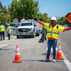 Road construction worker managing traffic with SLOW sign on suburban street