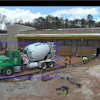Green cement mixer truck at construction site with workers preparing building foundation