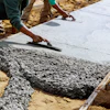 Workers smoothing wet concrete for sidewalk installation using professional trowels