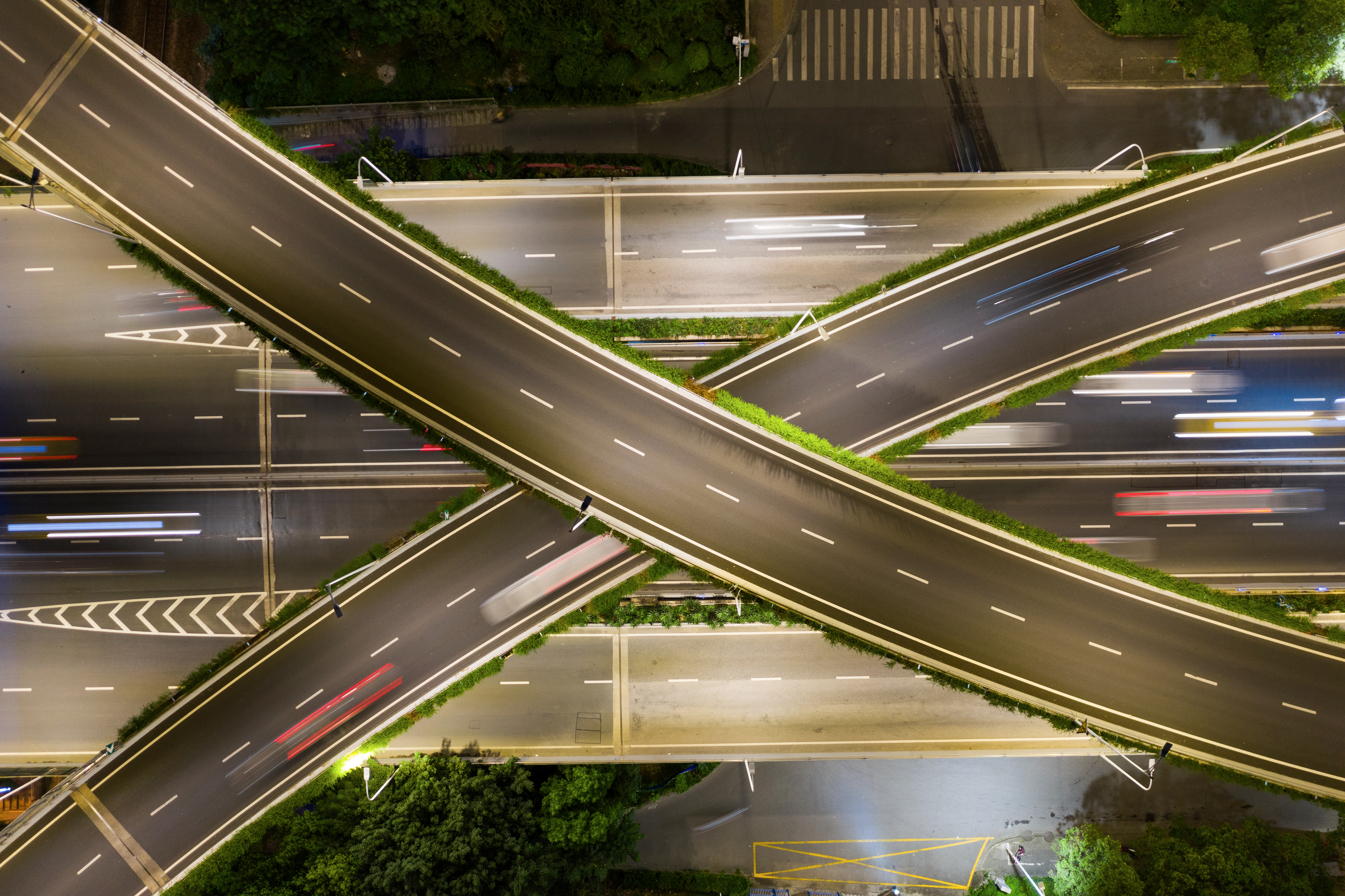 Nighttime aerial view of complex highway interchange with intersecting roads and light trails
