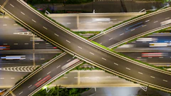 Nighttime aerial view of complex highway interchange with intersecting roads and light trails