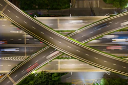 Nighttime aerial view of complex highway interchange with intersecting roads and light trails