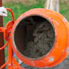 Orange concrete mixer with cement, ready for construction work