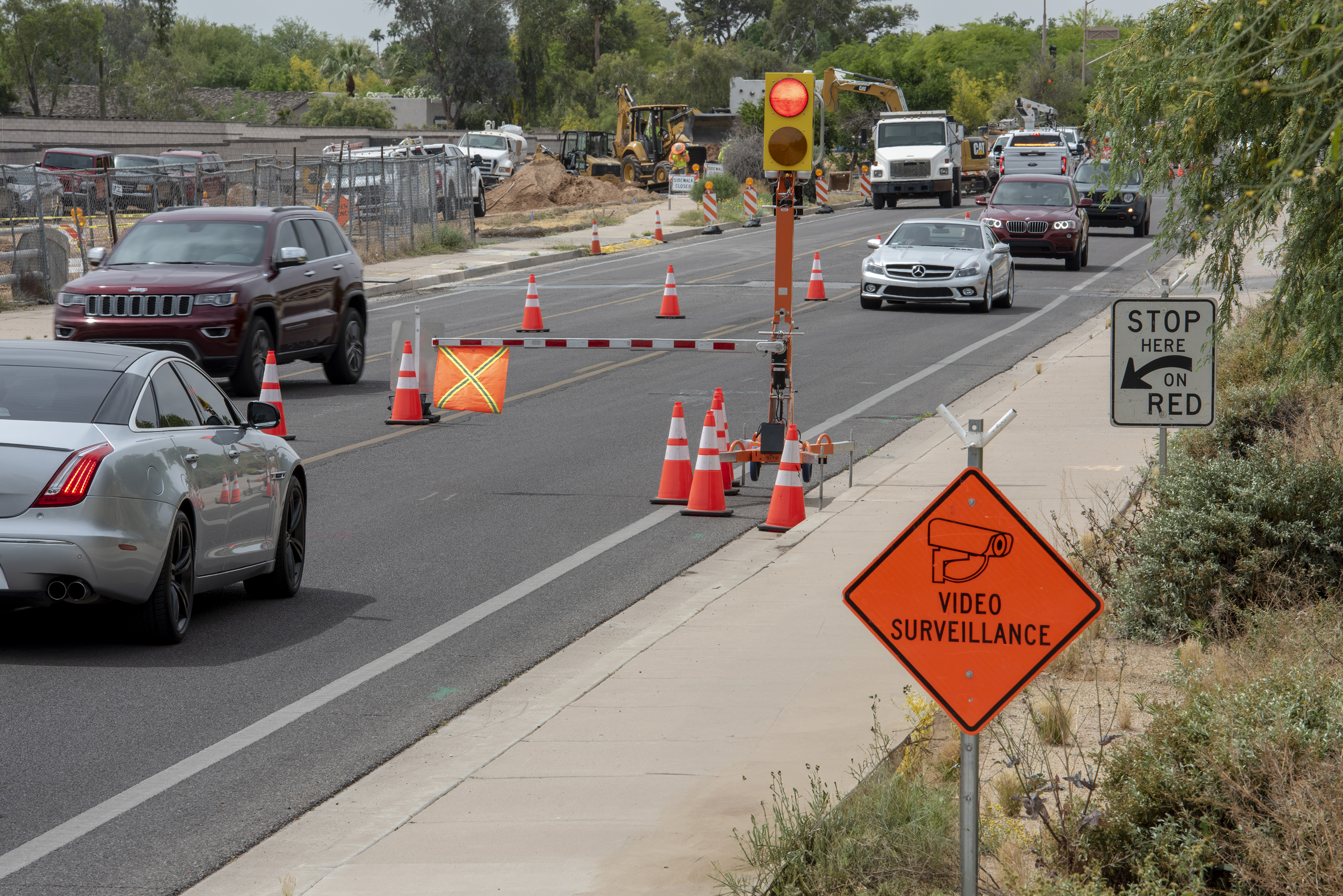 Road construction zone with safety cones, traffic signal, and vehicles navigating restricted lane