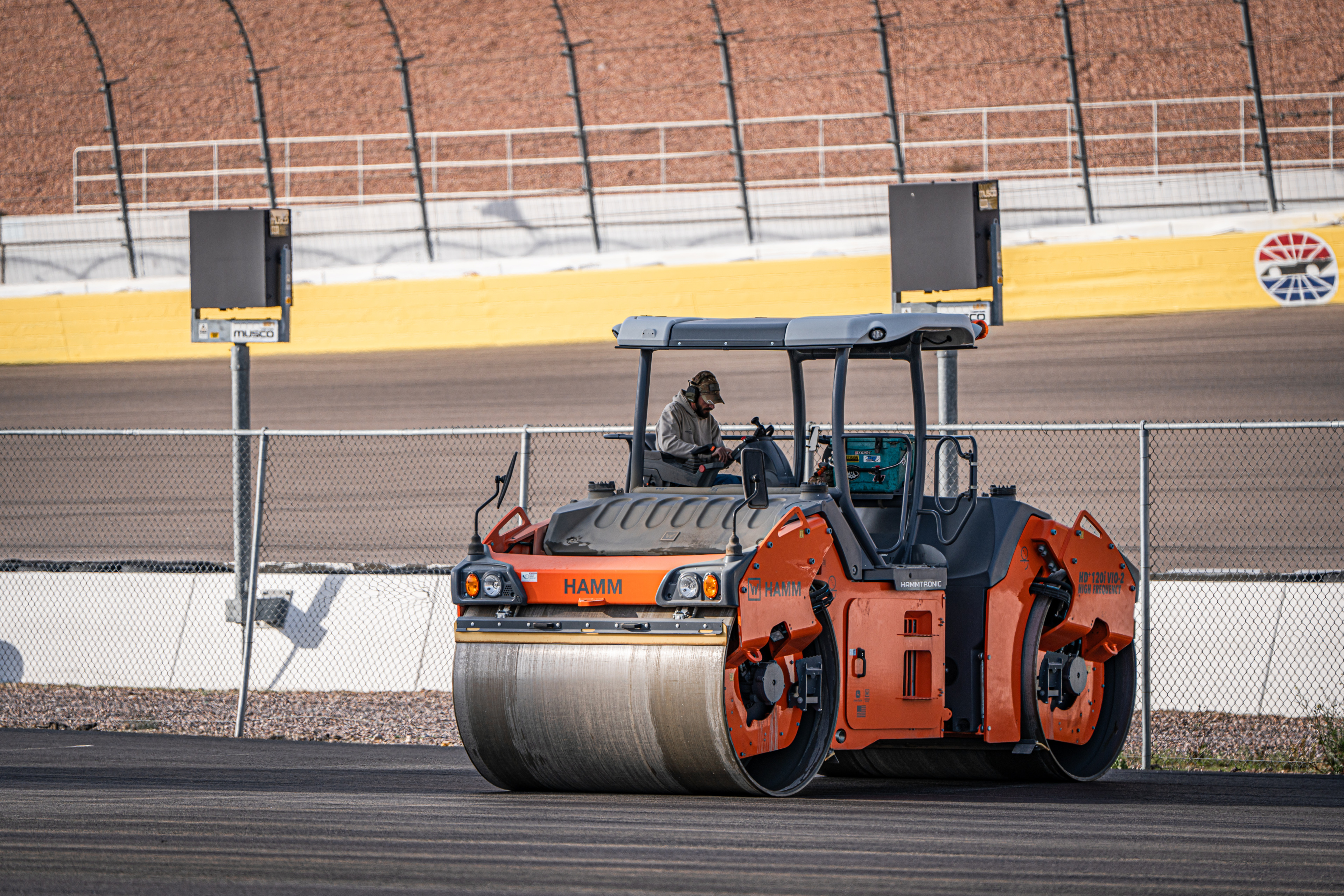 Orange Hamm road roller compacting asphalt on a racing circuit