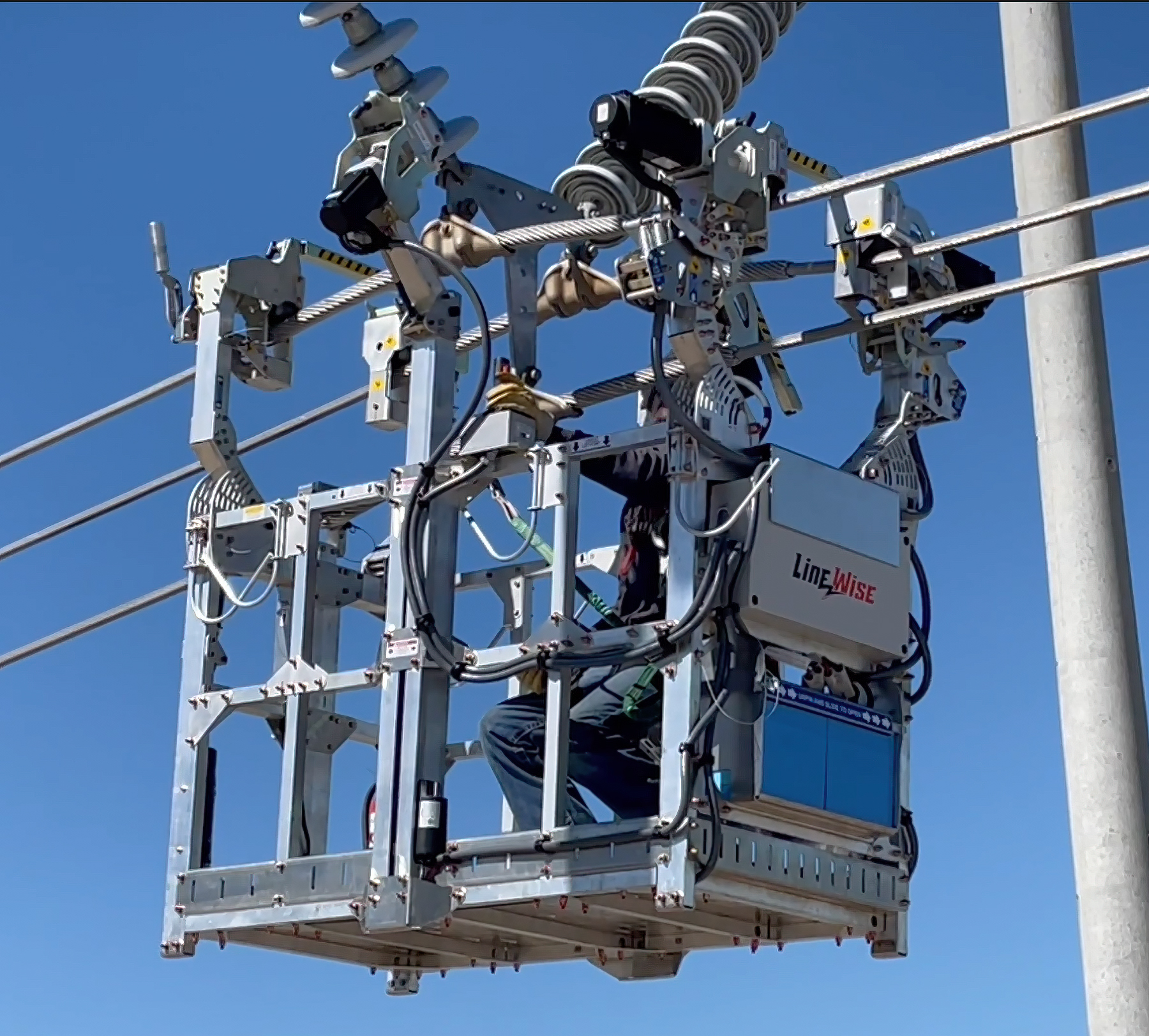 Utility worker in elevated bucket lift servicing power transmission lines