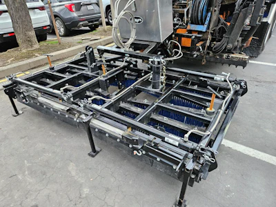 Road maintenance brush attachment with hydraulic mechanisms on industrial vehicle