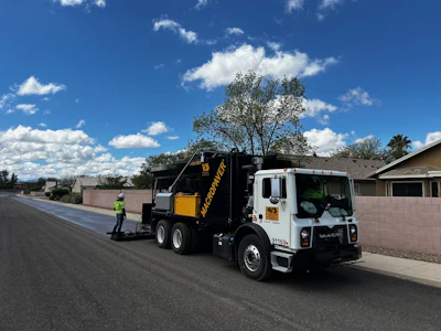 Road maintenance truck applying asphalt sealant on suburban street