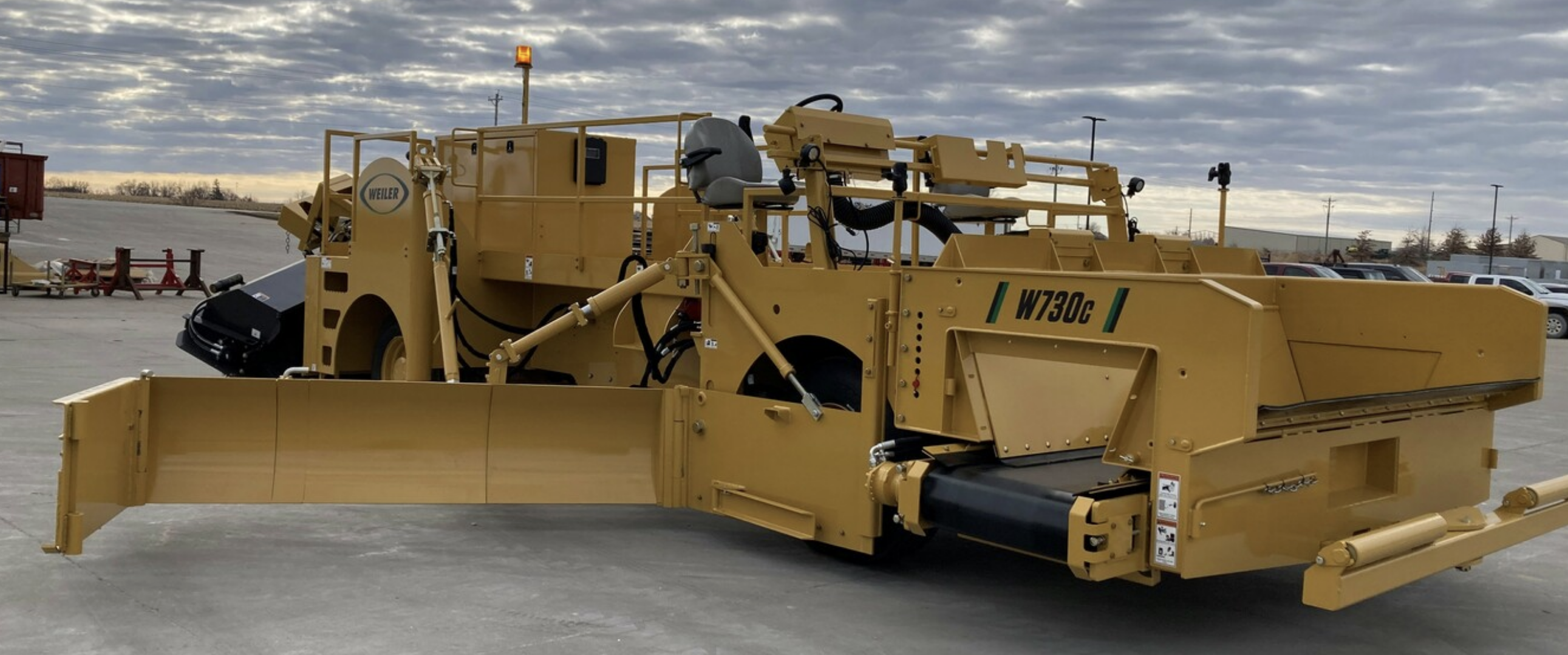 Yellow Weiler W730c road construction paver in industrial parking lot