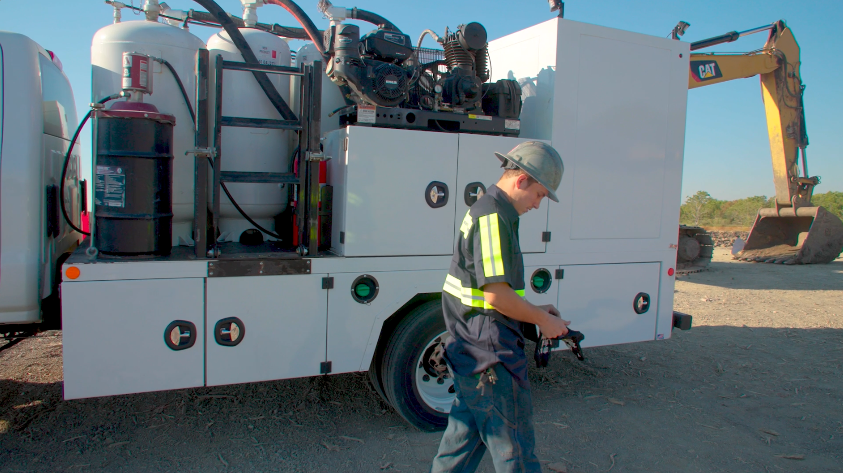 Industrial work truck with machinery and safety-vested worker at construction site