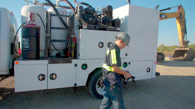 Industrial work truck with machinery and safety-vested worker at construction site