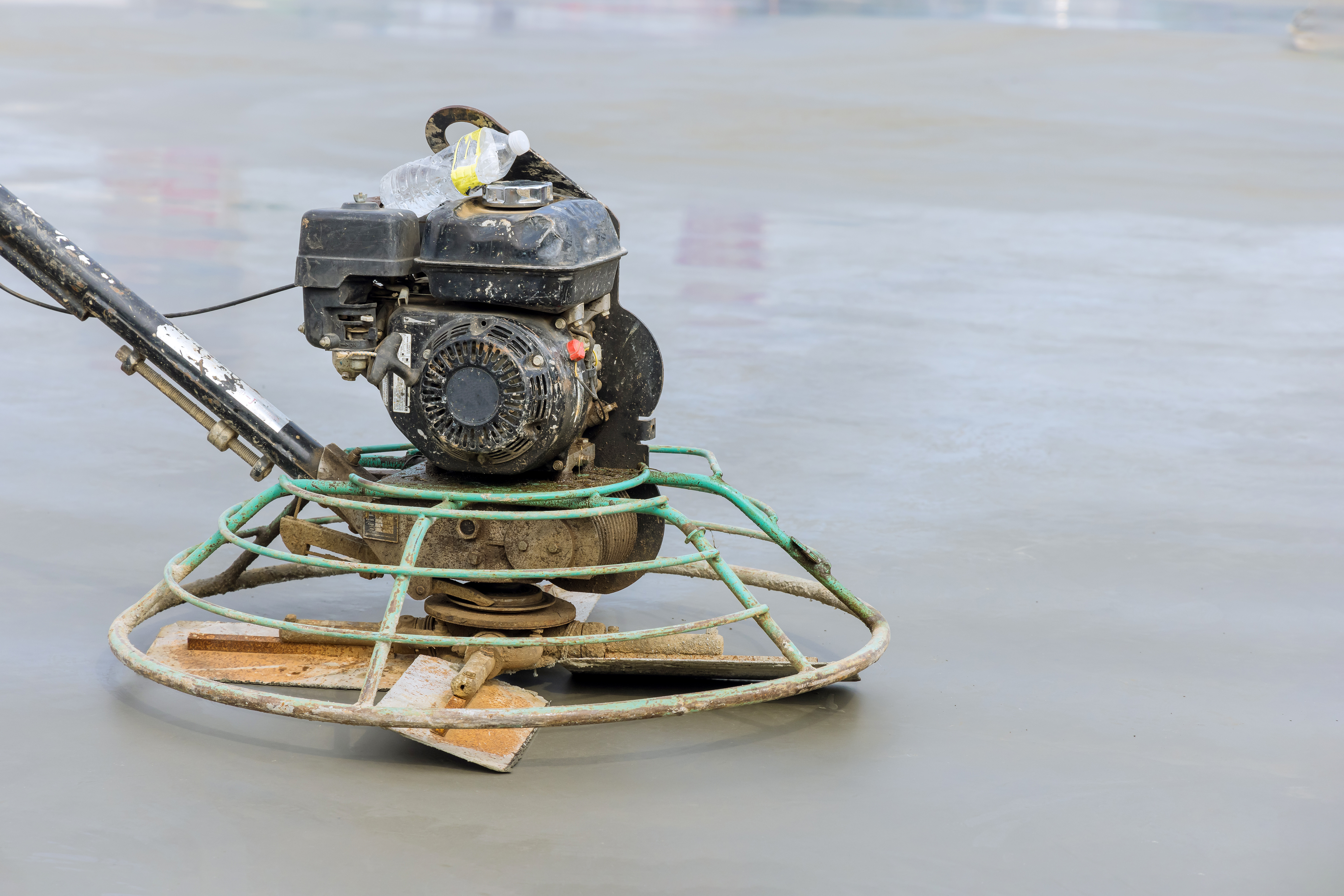 Construction power trowel on concrete with gasoline engine and circular metal frame