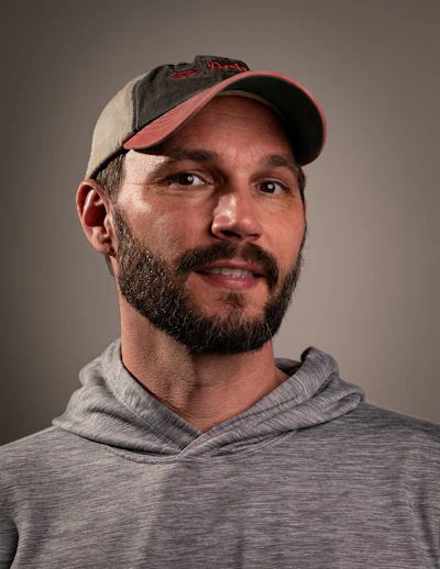 Man in baseball cap and gray hoodie looking slightly off-camera