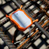 Orange protective sensor mounted on steel rebar with white document inside