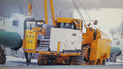 Heavy yellow tracked industrial vehicle in snowy construction site
