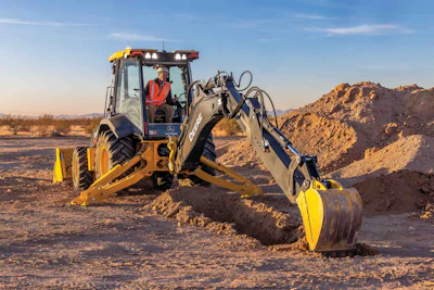 Yellow backhoe digging in desert terrain with yellow safety cones
