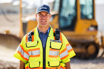 Construction worker in safety vest at job site with heavy machinery