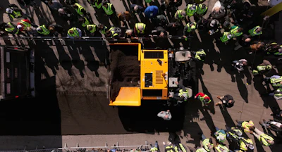 Aerial view of yellow utility vehicle amid workers in safety vests