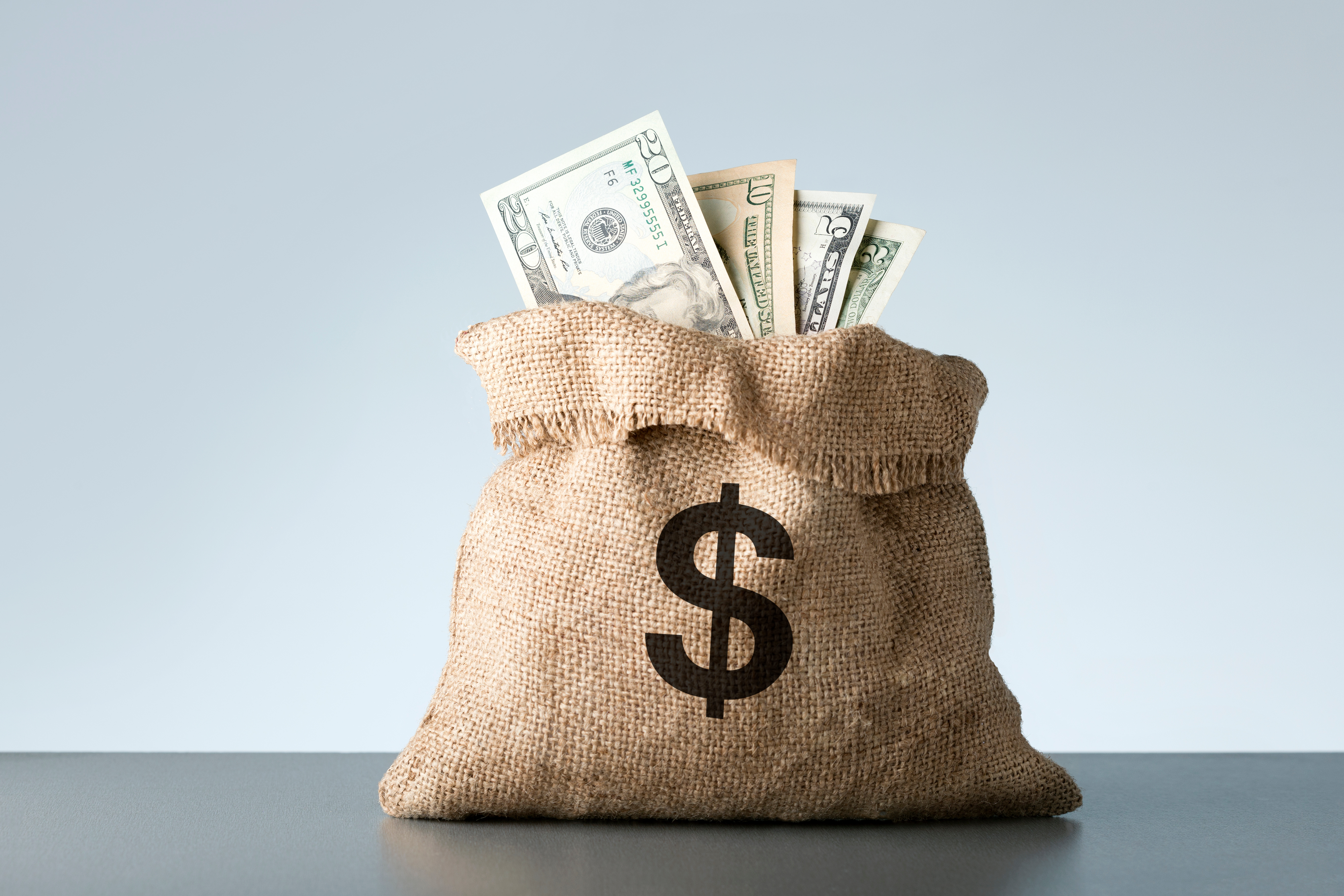 Burlap money sack with US dollar bills representing financial savings