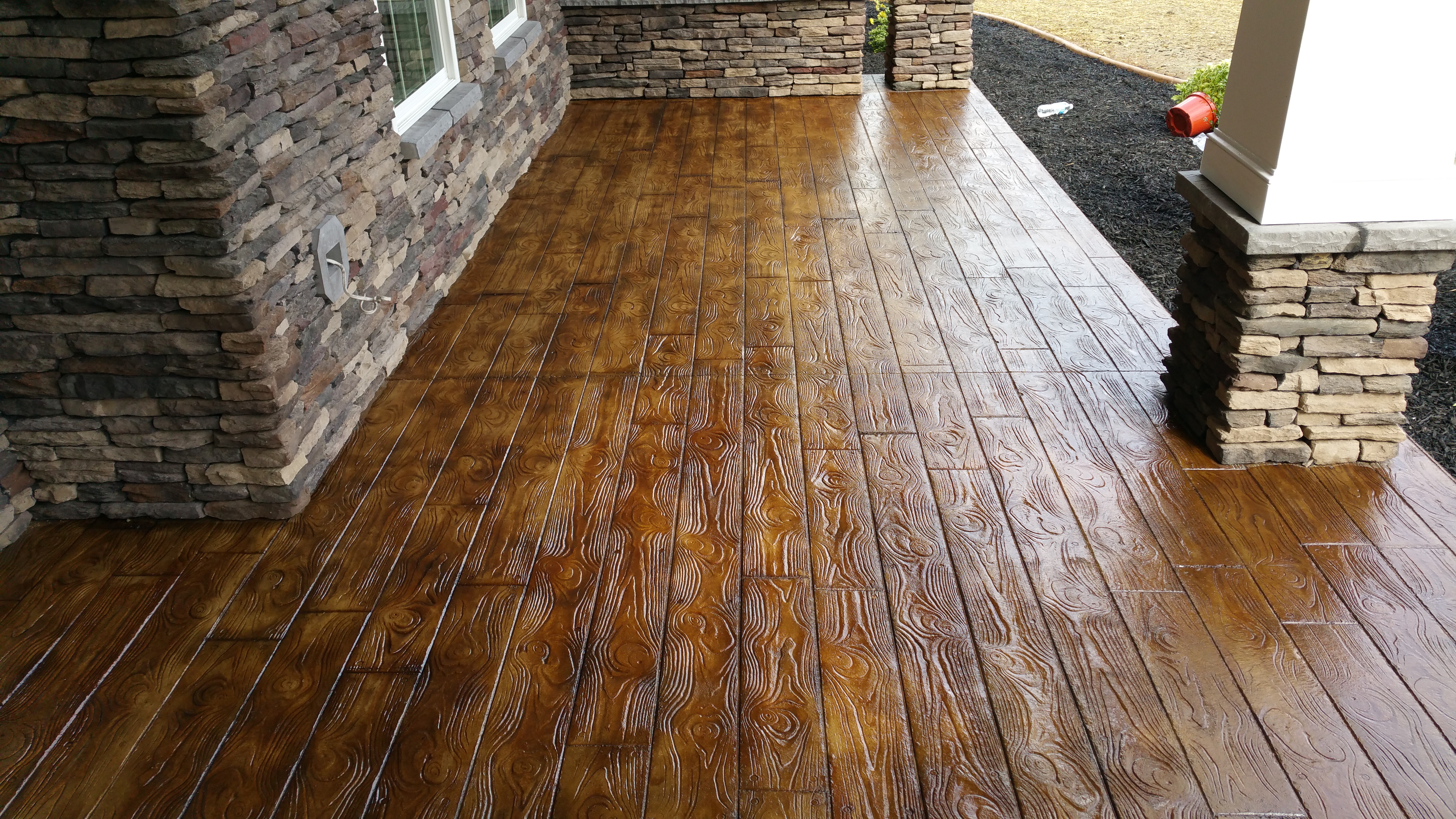 Wooden-textured stamped concrete patio with stone wall borders