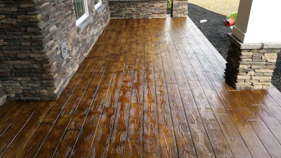 Wooden-textured stamped concrete patio with stone wall borders