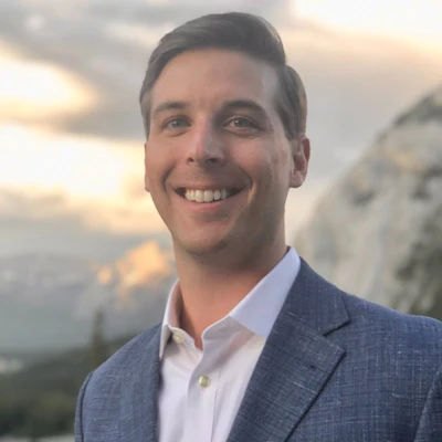 Smiling professional in blue blazer against cloudy sky backdrop