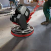 Construction worker using industrial floor polishing machine on concrete surface