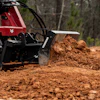 Yanmar construction machine moving red soil in wooded terrain