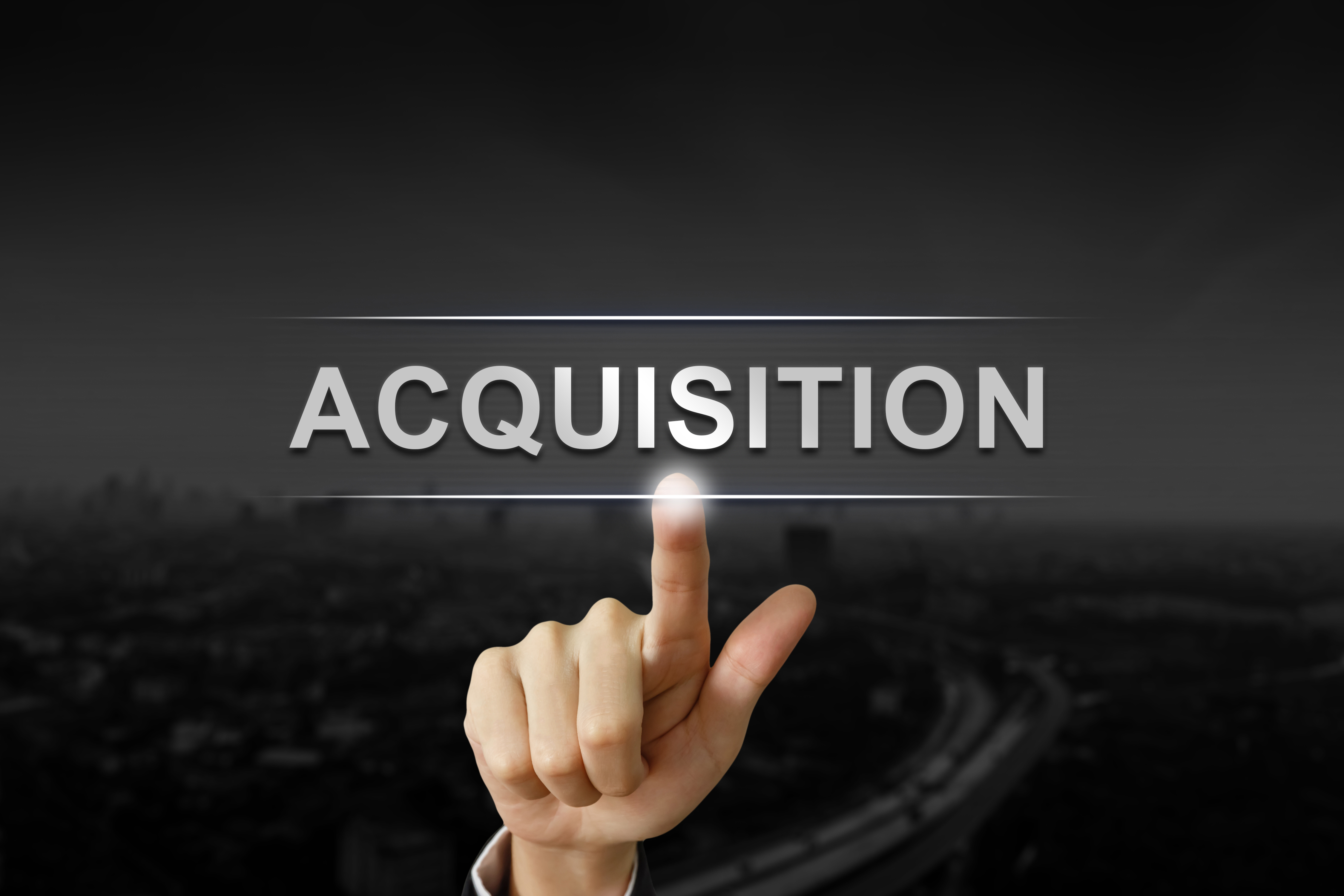 Hand pressing digital 'ACQUISITION' button on dark background