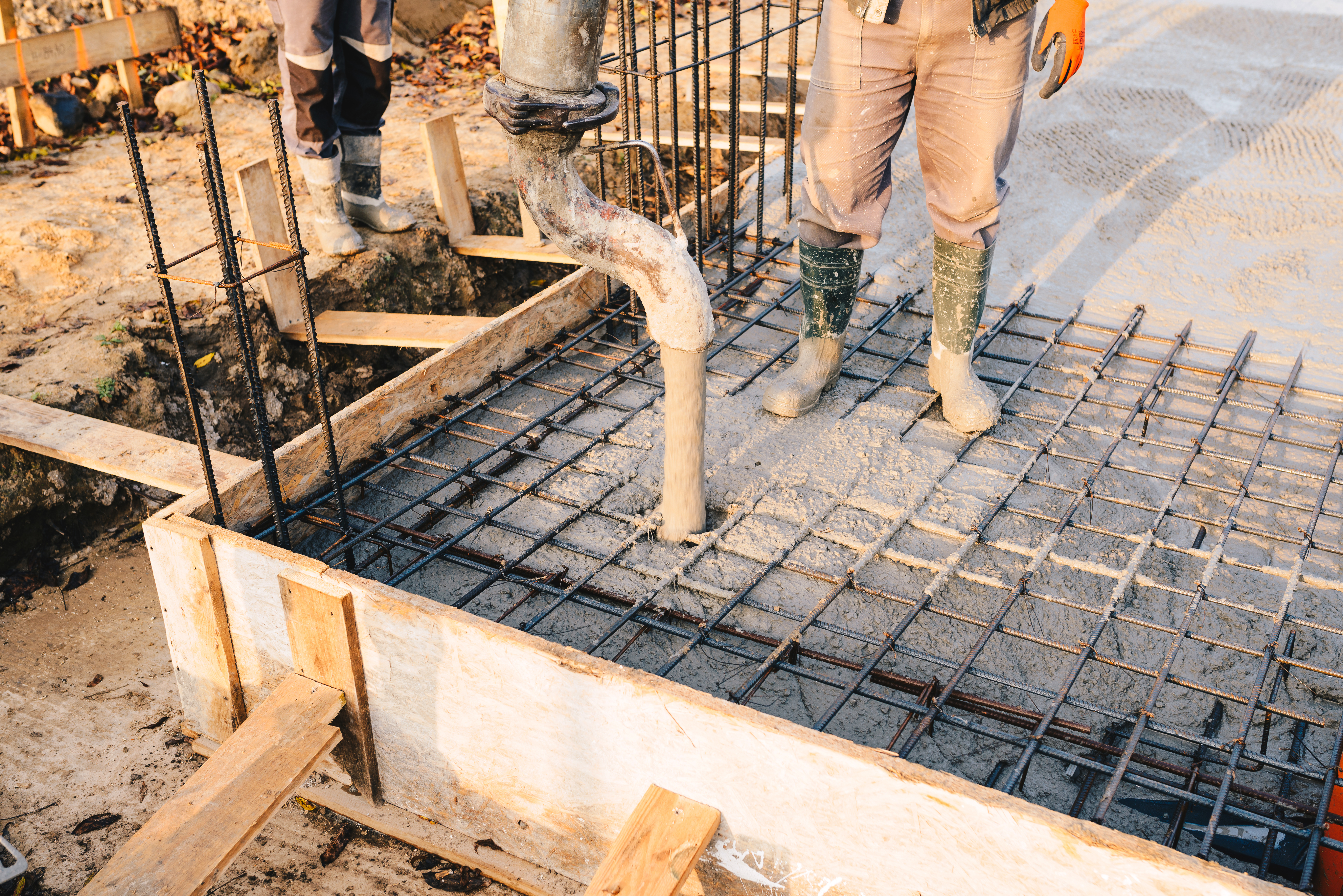 Construction workers preparing concrete foundation with steel reinforcement grid